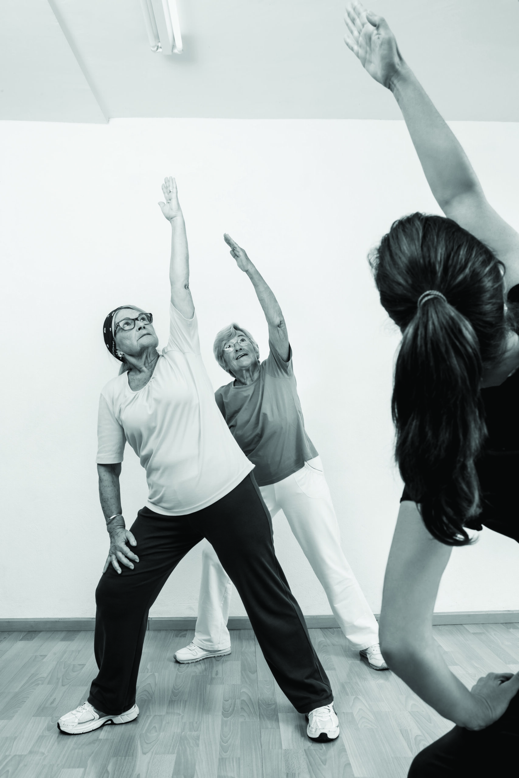 Two old women and instructor doing strech poses